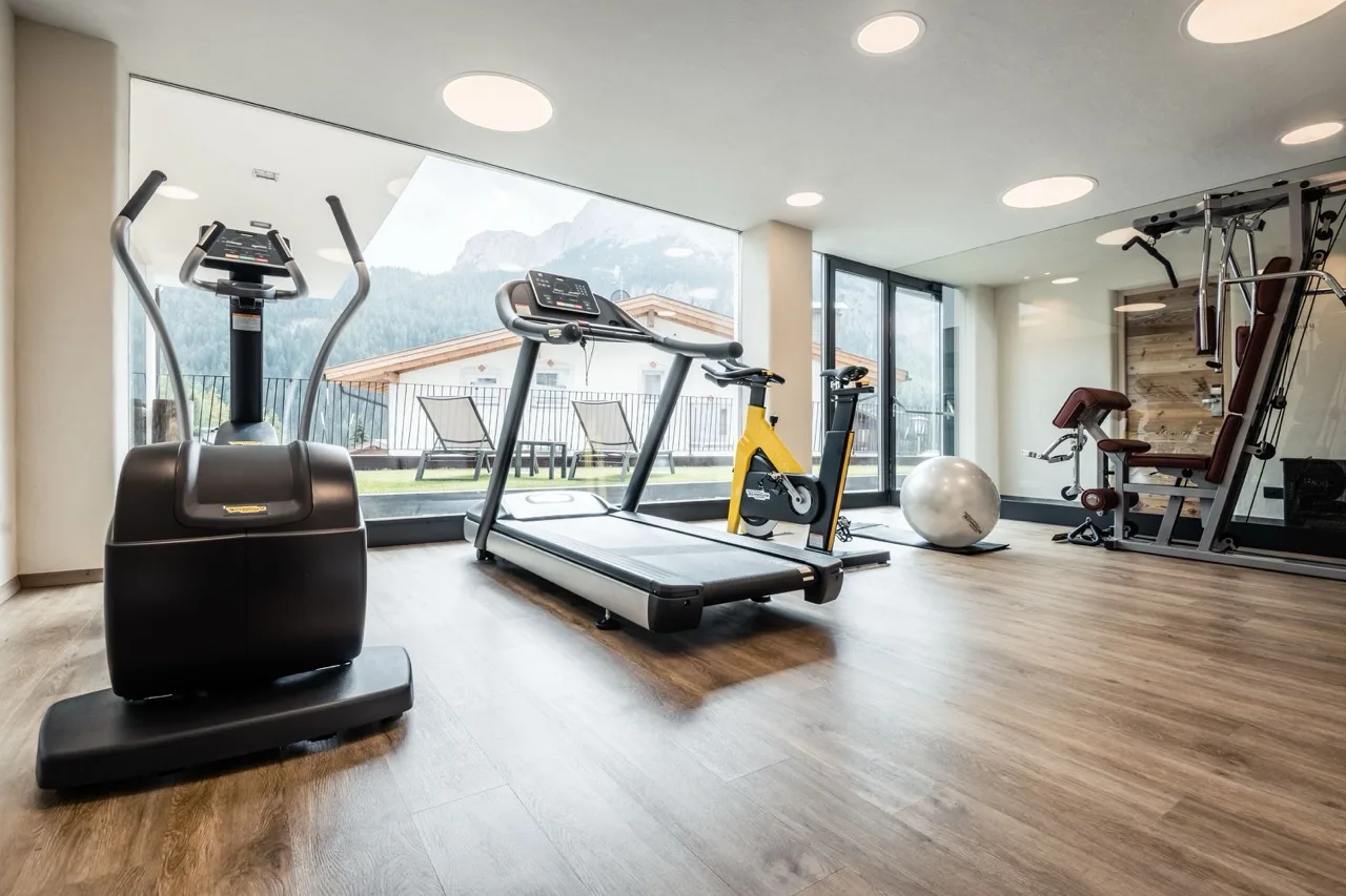 Gym at Hotel Gran Ciasa with large glass walls overlooking scenic mountain views