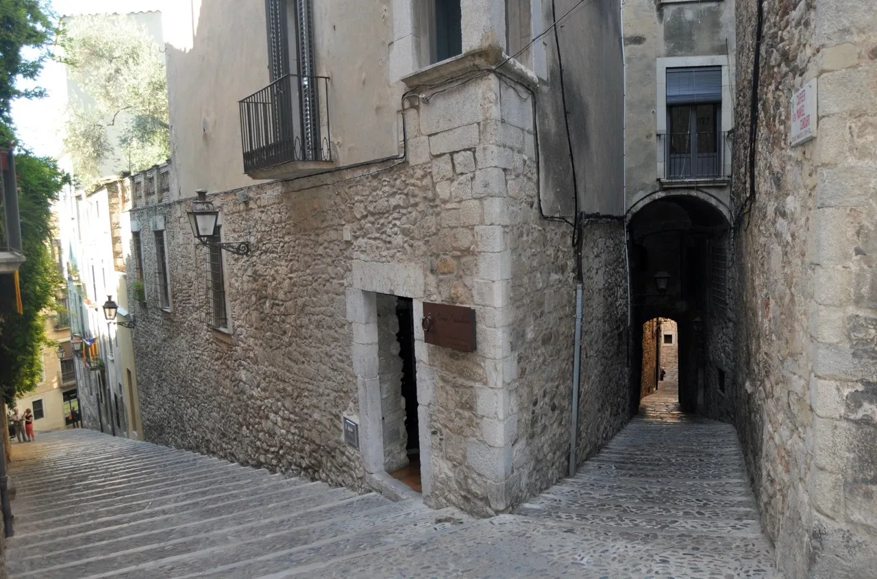 Exterior of Casa Cundaro in Girona, featuring historic stone walls and arched doorway in a narrow old-town street