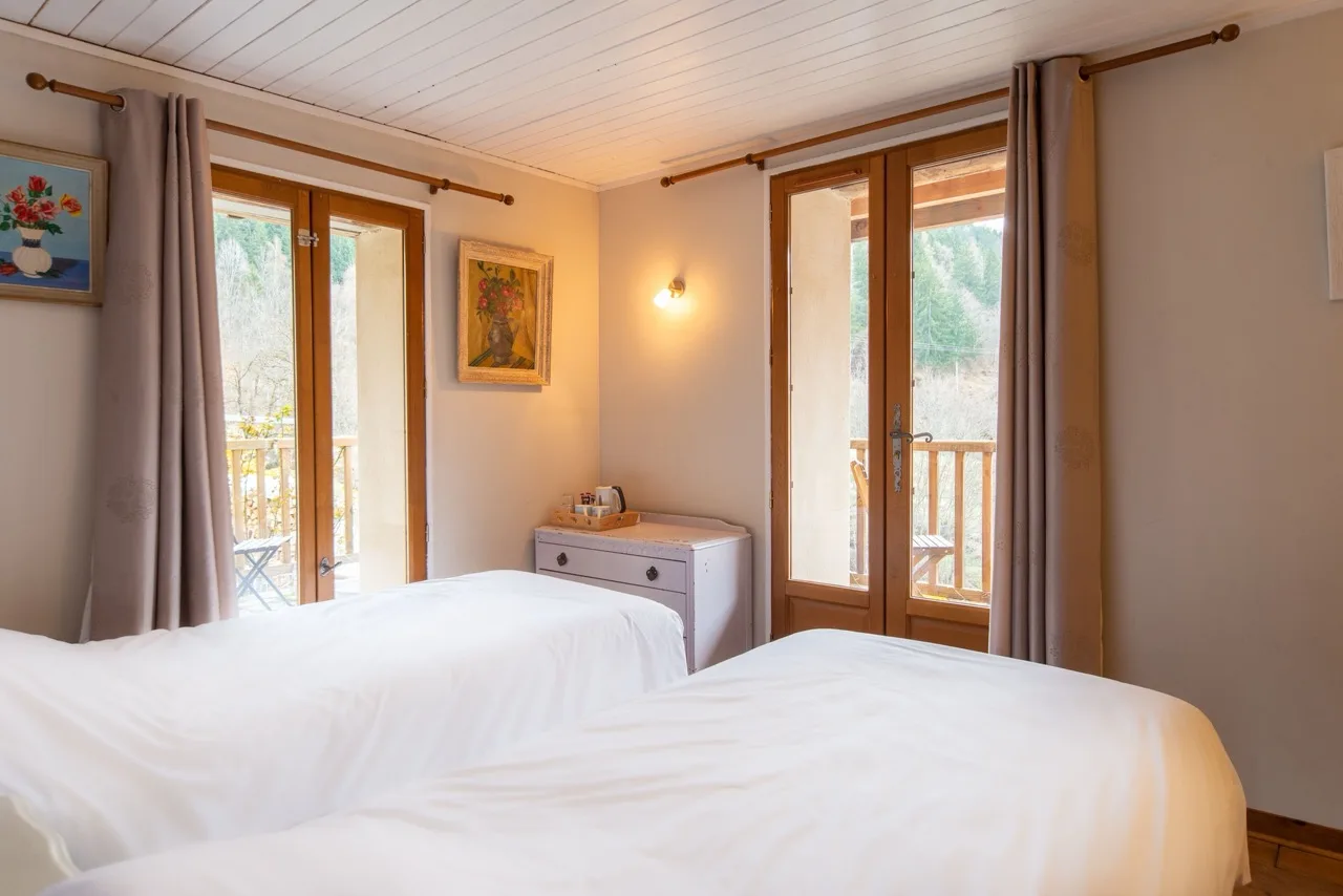 Clean bedroom with two white single beds and a balcony at Maison Caramel Landry
