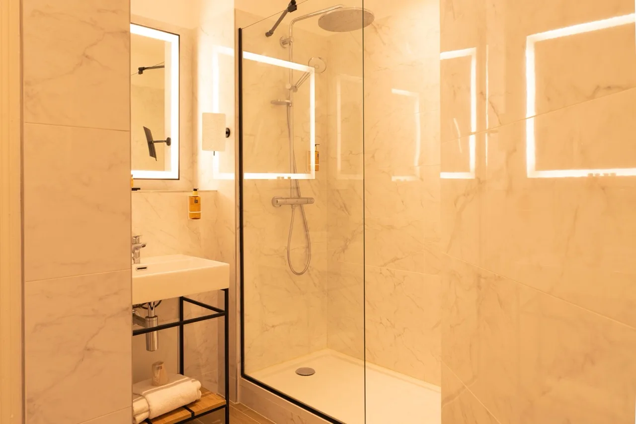 Bathroom at Hôtel D'Anjou Angers with modern design, shower, and warm lighting