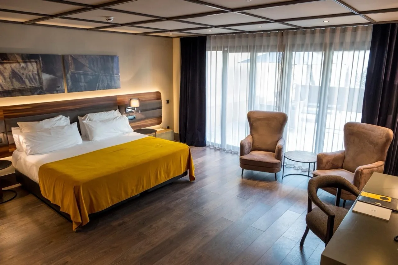 Spacious brown-themed bedroom at Hotel Nord 1901 in Girona, featuring a large white bed and warm lighting