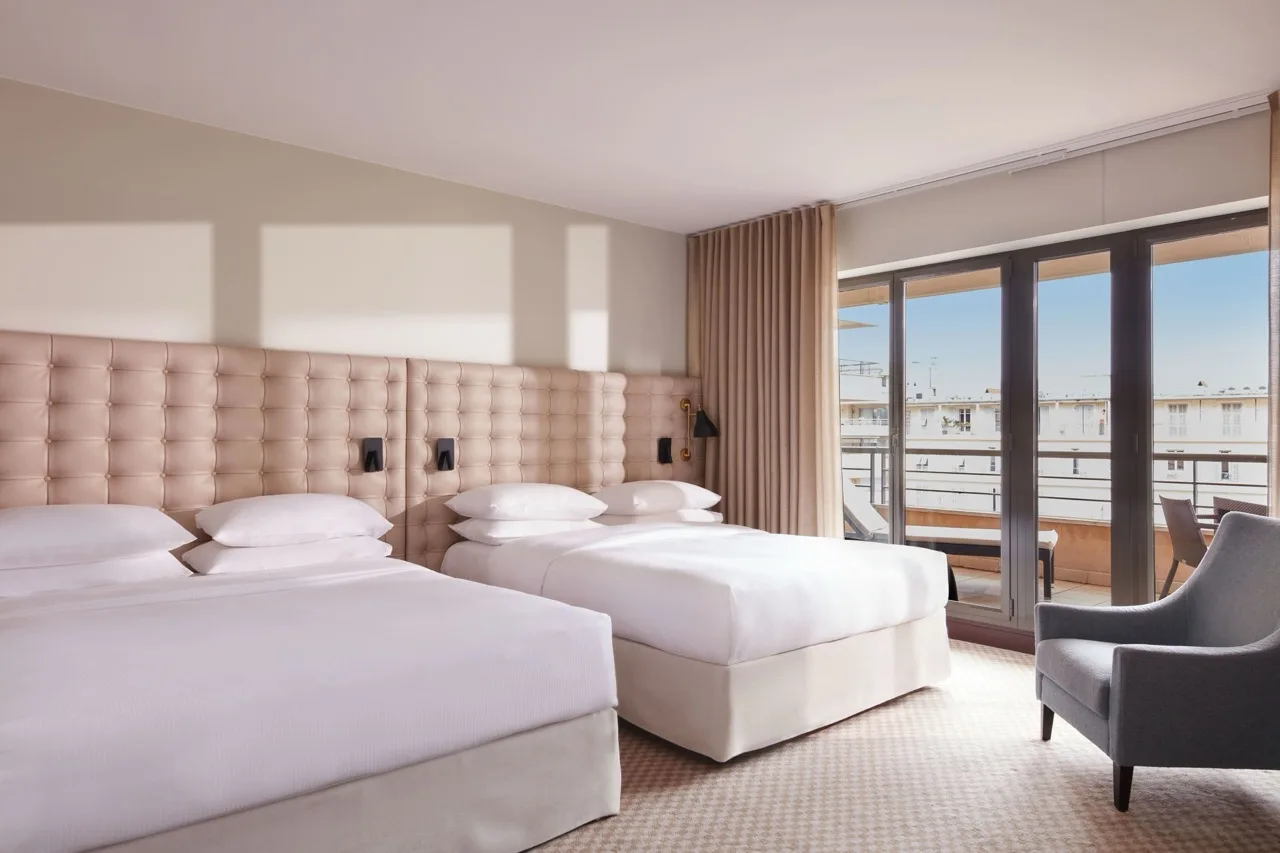 Bedroom at Hyatt Regency Nice Palais de la Méditerranée with two queen beds, glass balcony divider, modern white and light brown design