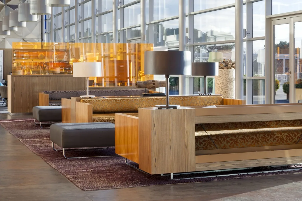 Modern lounge at Hotel Palau de Bellavista Girona by URH with wood sofas, lamps, bar, and large glass windows