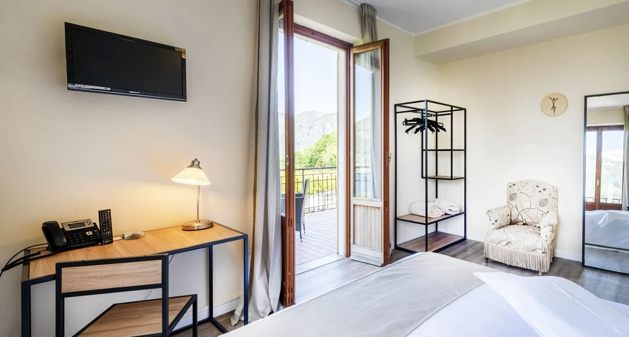 White bedroom at Hotel Il Perlo in Bellagio with wooden furniture and a bright, airy atmosphere
