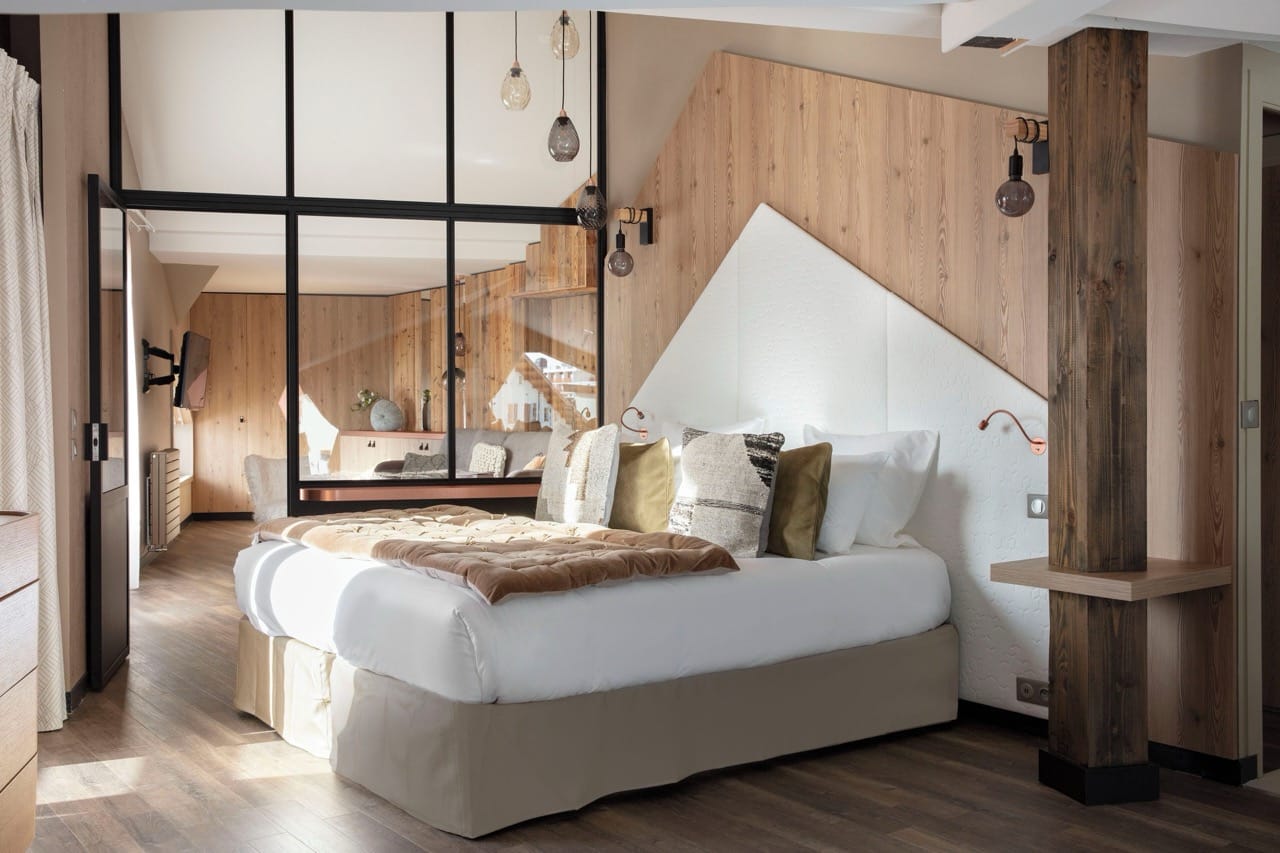 Bedroom at Grandes Rousses Hotel & Spa with rustic wood design, white bed, and cozy warm interior
