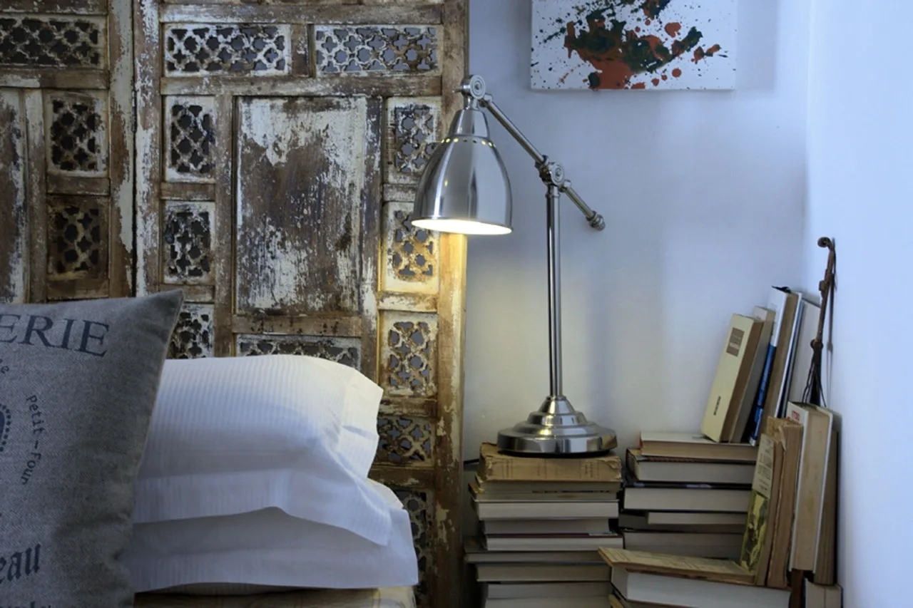 Photo of the headboard showing pillows, rustic wooden design, books, and a side lamp