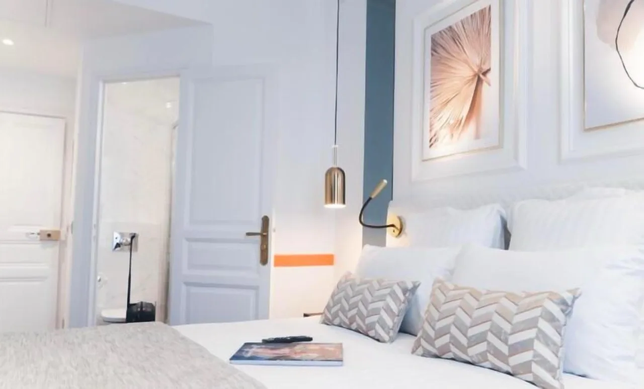 Bedroom at Hôtel D'Anjou, Angers, featuring white walls and white furniture in a minimalist style