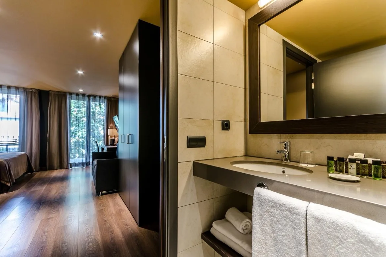 View from bathroom at Hotel Nord 1901 in Girona with large mirrors, sink, and partial view of the bedroom beyond