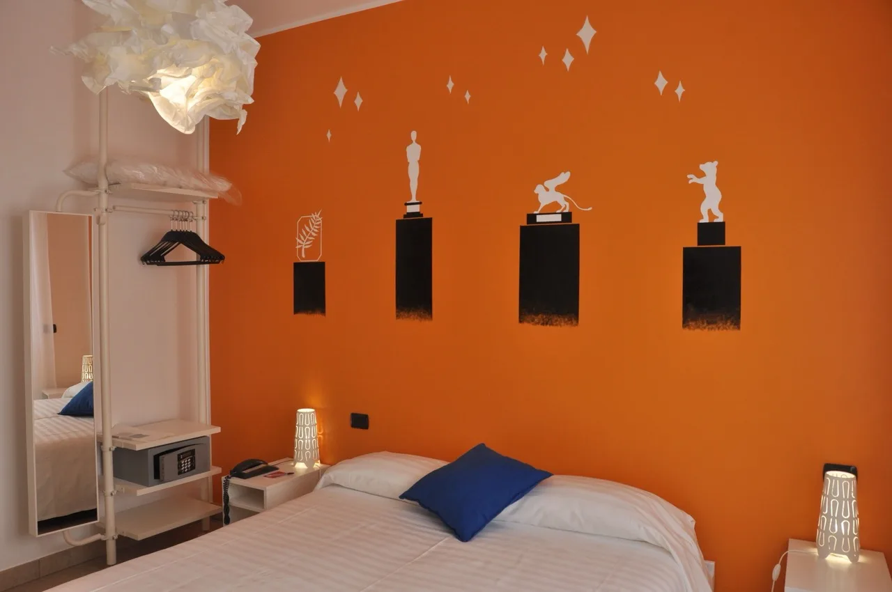 Bedroom at Lo Scoiattolo Piedmont Bike Hotel in Pralormo with orange walls, white bed, and white furnitures