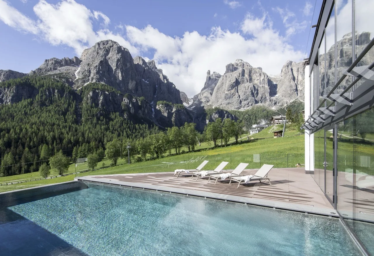 Outdoor pool at Hotel Cappella in Colfosco with stunning mountain views in the background