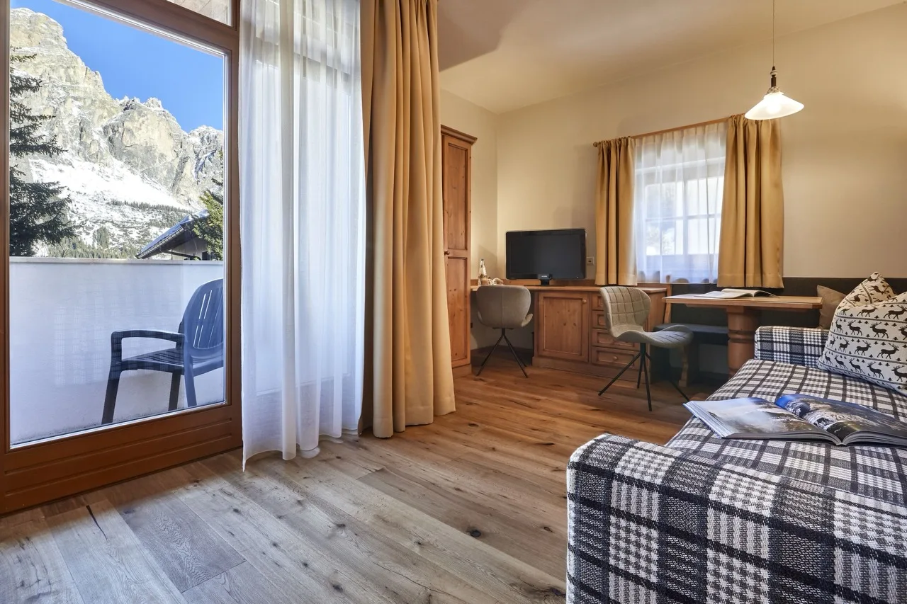 Living room at Hotel Marmolada with patterned sofa and large sliding glass door overlooking mountains