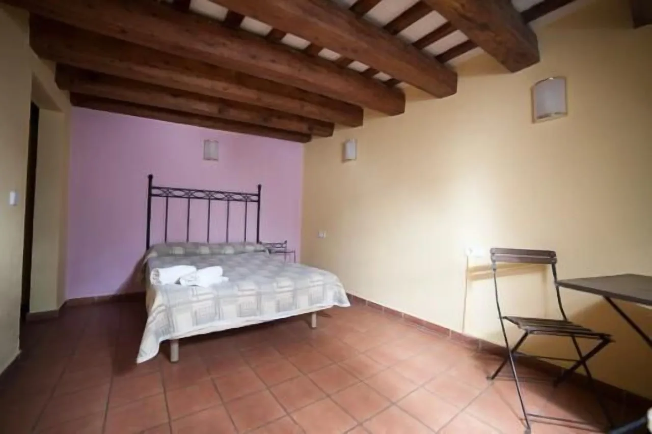 Spacious bedroom at Peninsular Hotel in Girona with minimal design, bed, and small chair with side table