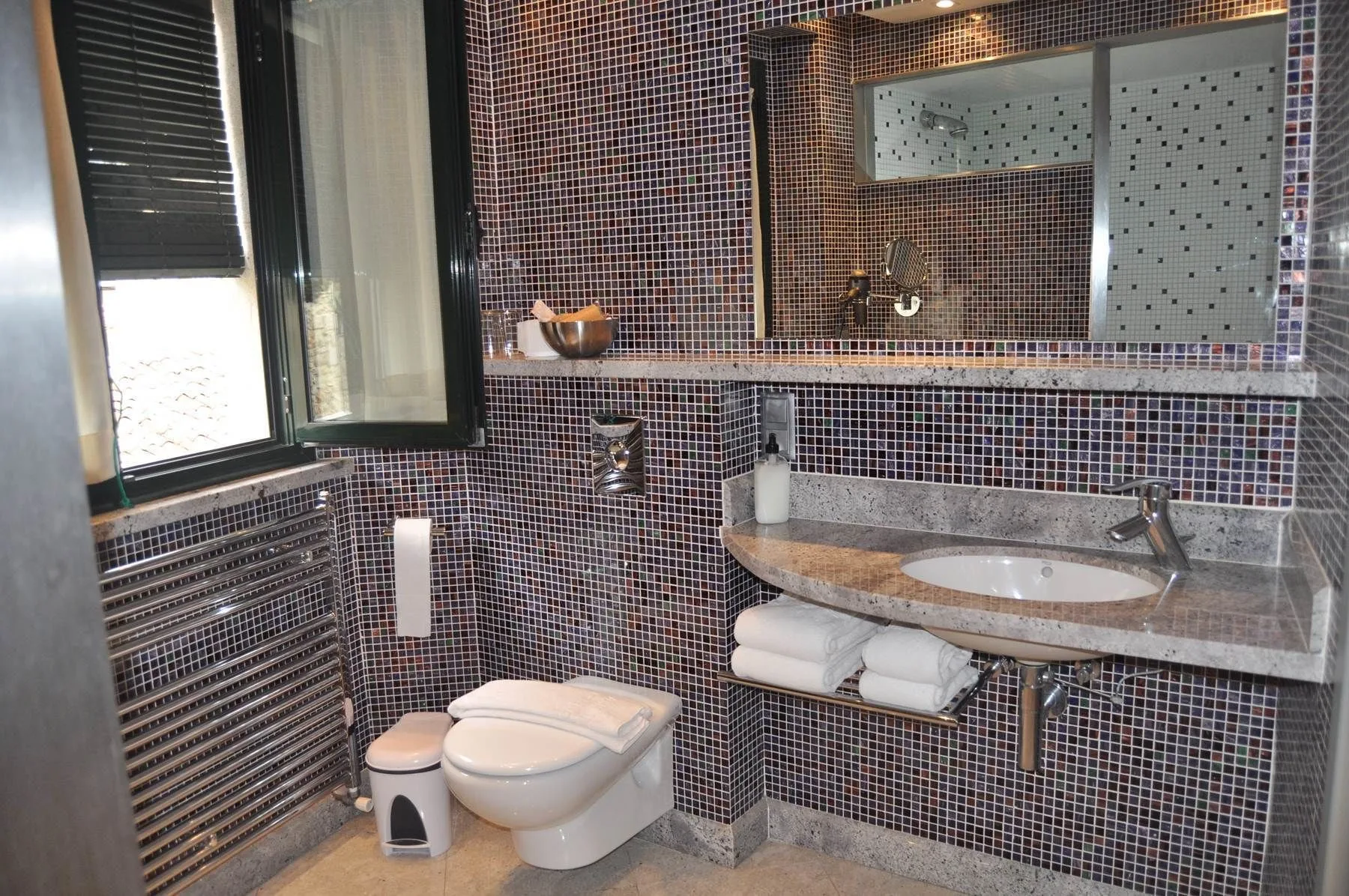 "Bathroom with small square black tiles, modern fixtures, and a sleek, minimalist design