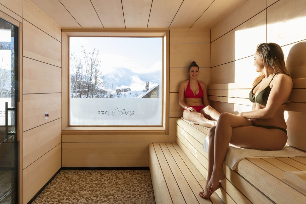 Wooden sauna interior at Grandes Rousses Hotel and Spa with two girls relaxing in two piece swimwear