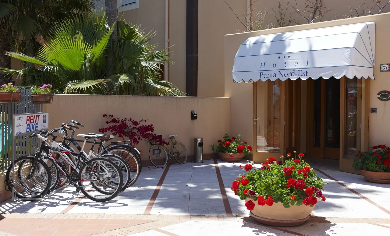 Entrance view of Hotel Punta Nord Est Castellammare del Golfo with bikes parked in front beside the "rent bike" signage