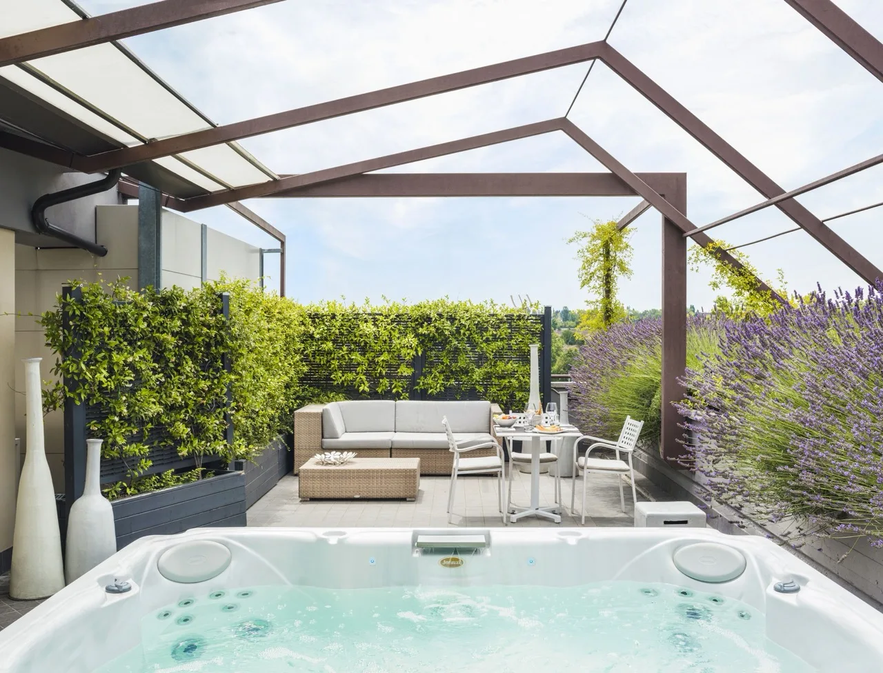 Jacuzzi at Lake Garda Bike Hotel with glass roof, greenery, sofa, and coffee table in the back