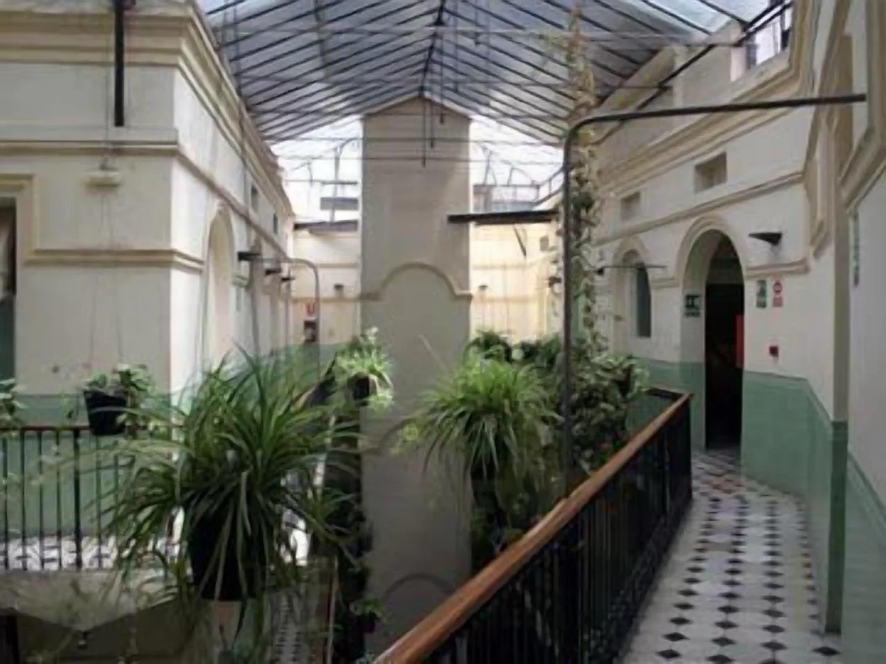 Indoor walkway at Peninsular Hotel in Girona with black & white checkered tile floor, green plants, & arched doorways