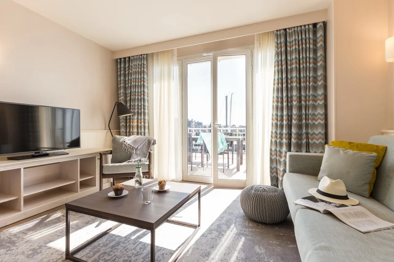 Modern living room with glass doors to balcony at Residence Pierre & Vacances Premium Presqu'Ile de la Touques