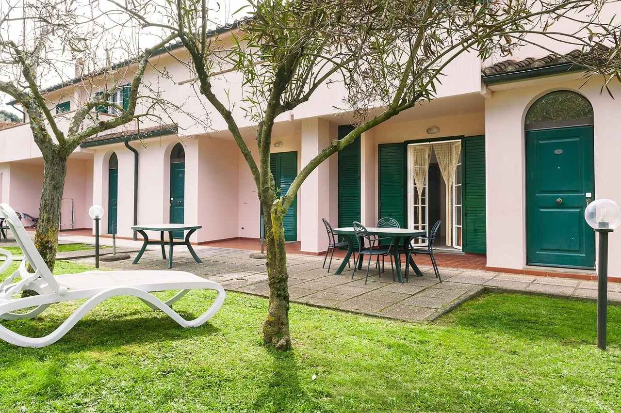 Exterior of Massa Vecchia in Massa Marittima with light peach-coloured walls and green windows and doors