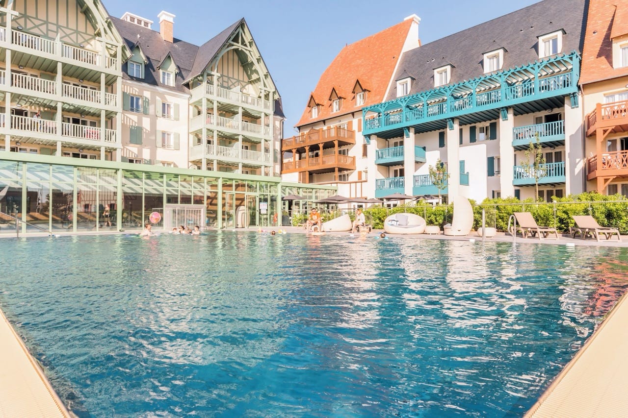 Outdoor pool at Résidence Pierre & Vacances Premium Presqu'Ile de la Touques with hotel buildings in the background