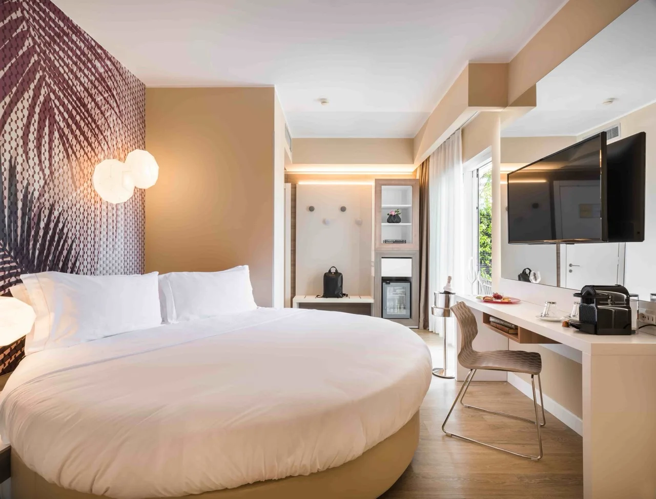 Circular white bed at Lake Garda Bike Hotel with light brown walls and wood-style vinyl floor