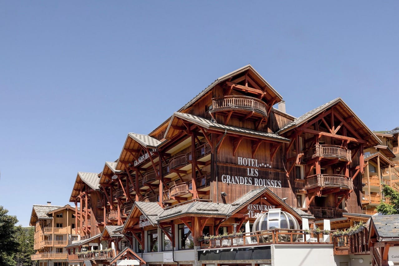Exterior of Grandes Rousses Hotel & Spa in L'Alpe-d'Huez with rustic wood design and balconies