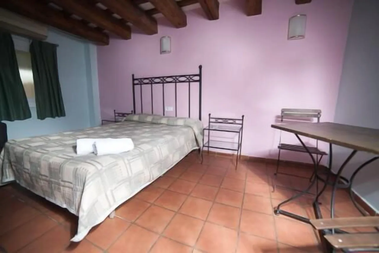 "Bedroom at Hotel Peninsular in Girona with single bed, pastel purple and blue walls, and vintage wood furniture