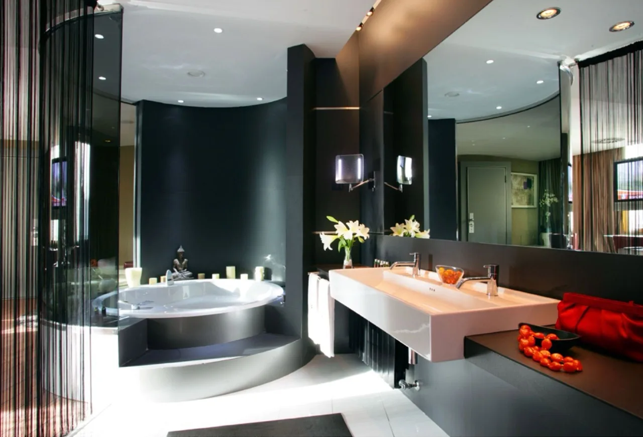 Modern bathroom at Carlemany Girona with black walls, large mirrors, and a white bathtub in sleek design