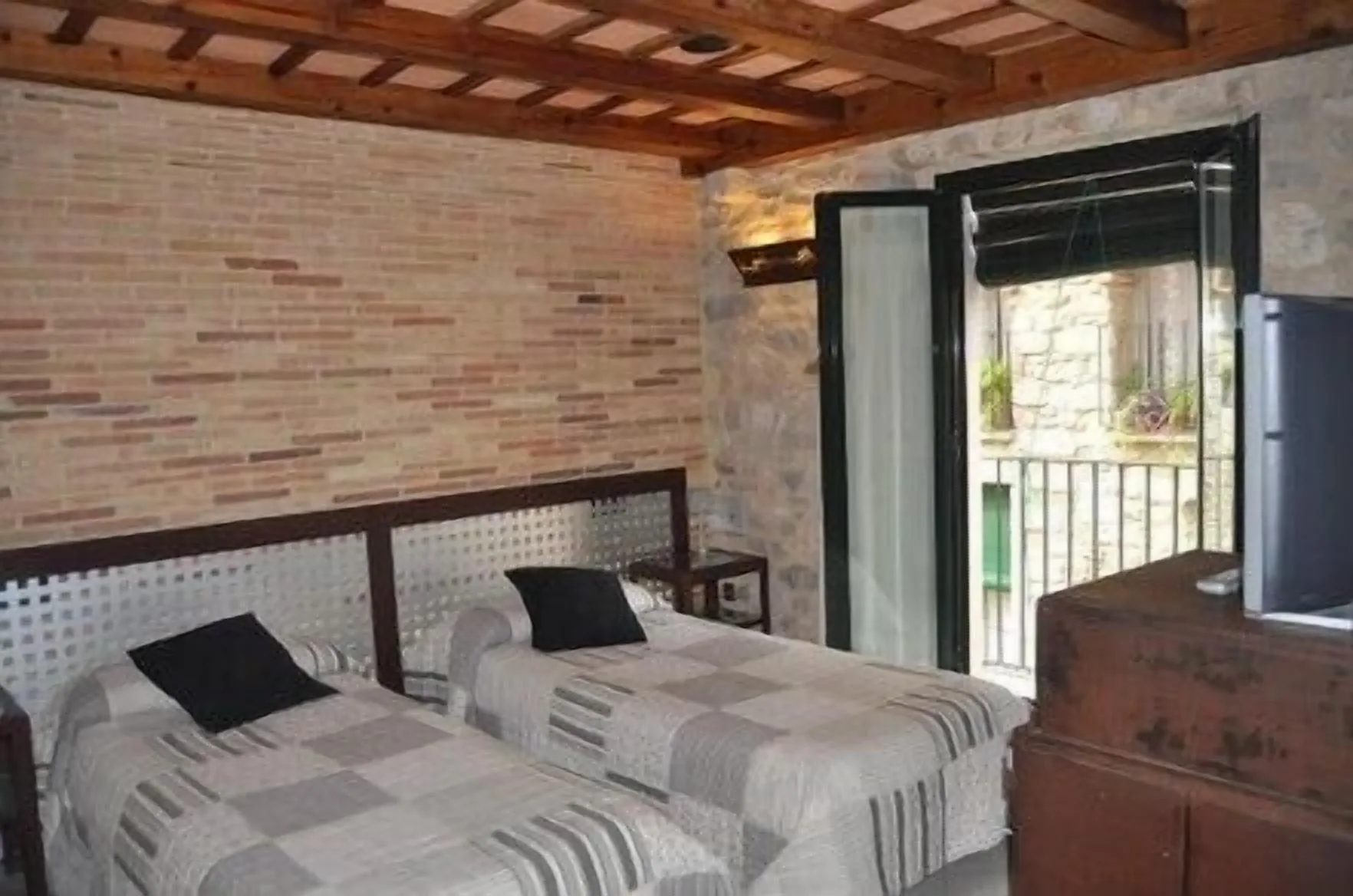 Small bedroom at Hotel Històric in Girona with two beds and large two-door balcony access