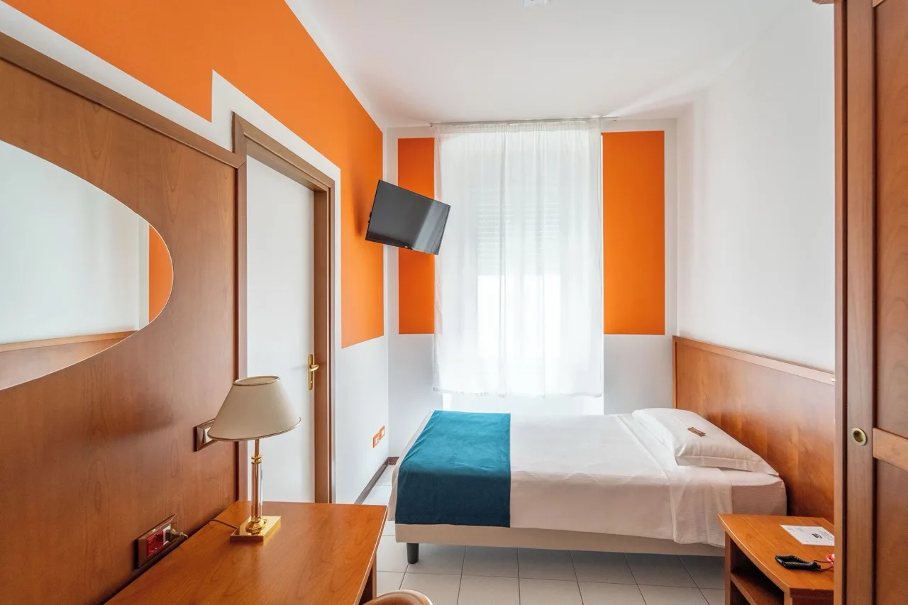 Bedroom at Hotel Italia with white and orange walls, wood accents, and South Tyrol décor