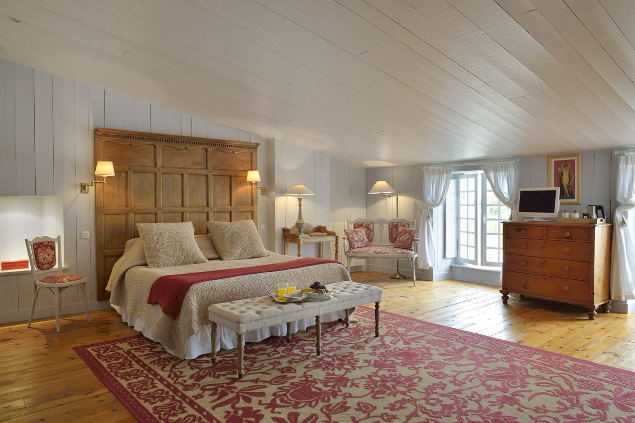 Bedroom at La Baronnie Hôtel & Spa Teritoria Saint-Martin-de-Ré with wooden floor, large rug, and vintage style furnishings