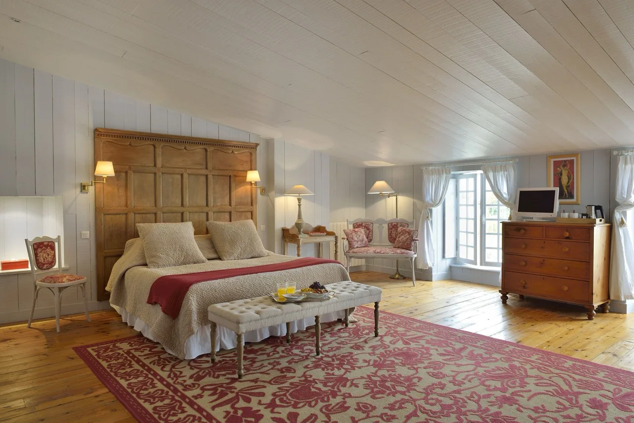 Bedroom at La Baronnie Hôtel & Spa Teritoria Saint-Martin-de-Ré with wooden floor, large rug, and vintage style furnishings