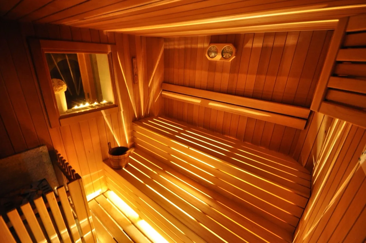 Sauna with wooden design at Hotel Al Forte in Arabba featuring warm lighting and bench seating