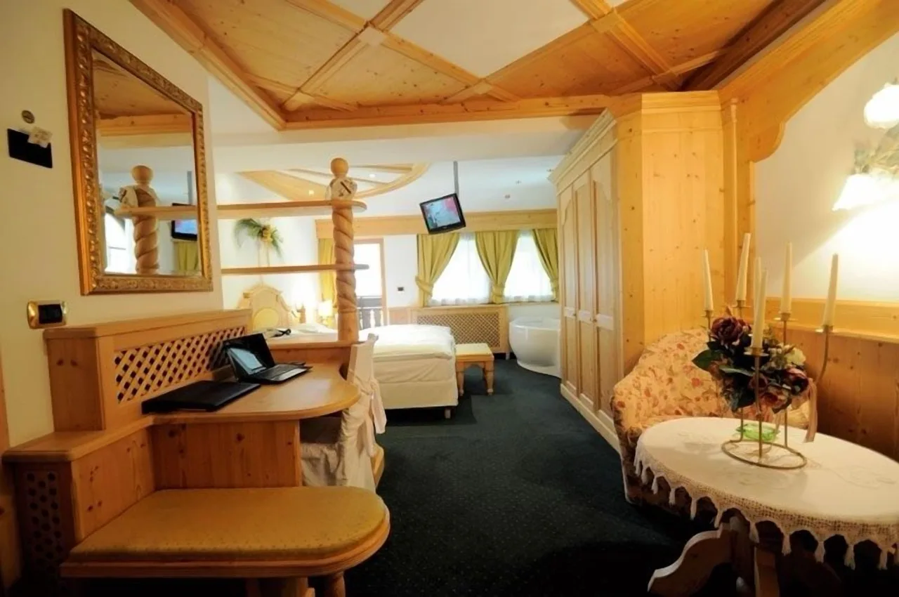 Suite at Hotel Al Forte in Arabba with wooden theme, white walls, desk, and bed in the back