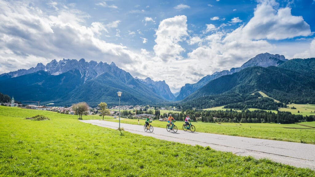 Cyclists riding together through a Dolomites valley in Italy with towering limestone mountains