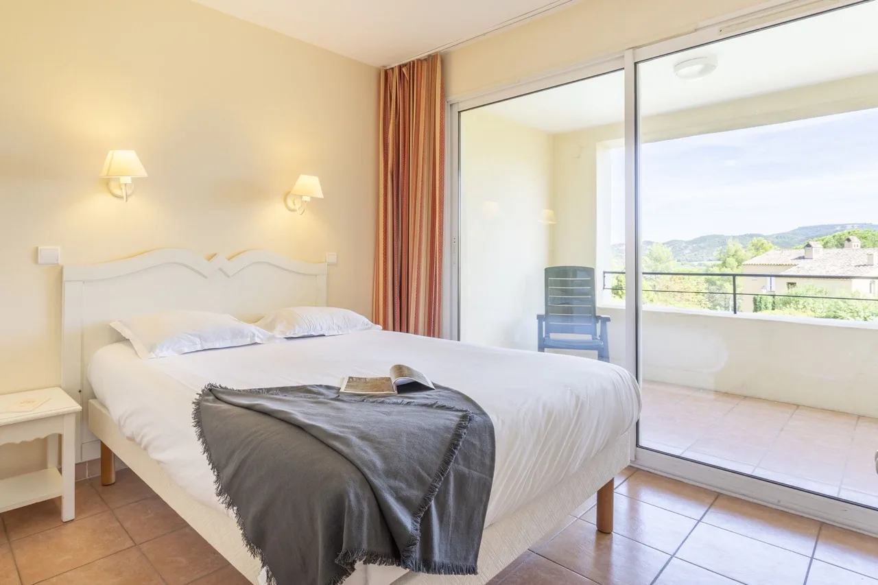 Minimalist bedroom with glass sliding doors and balcony at Village Pierre & Vacances Pont Royal en Provence