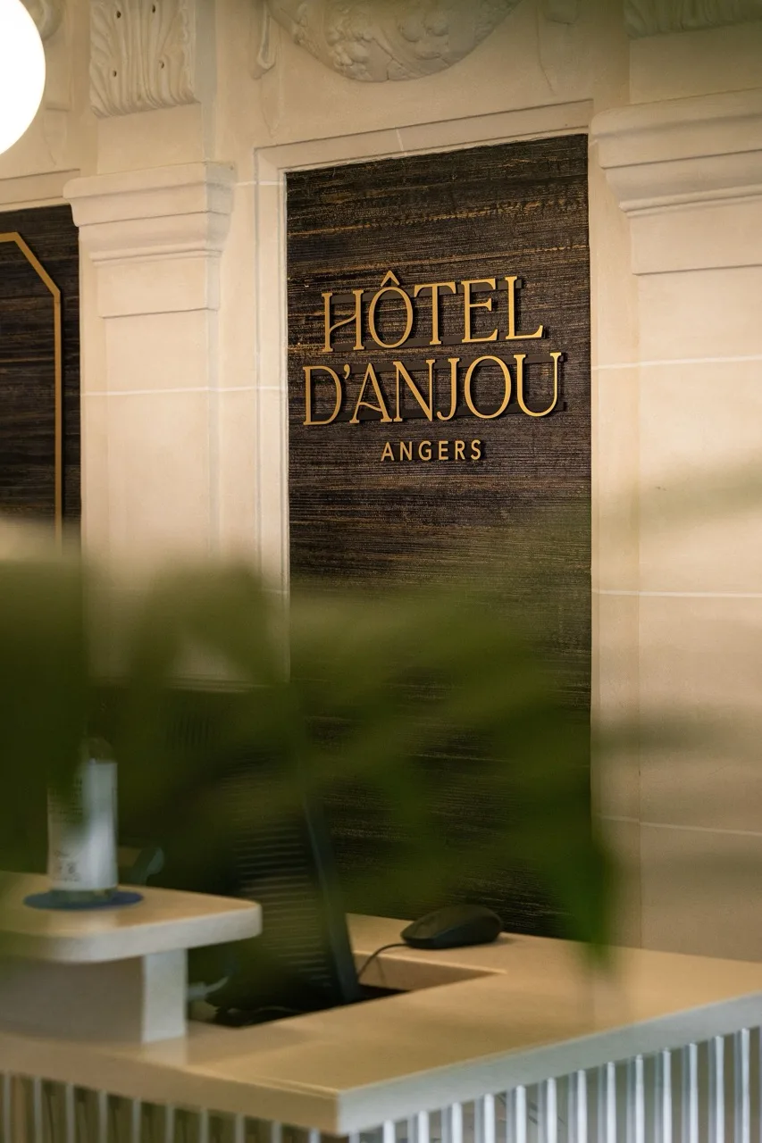 Reception desk at Hôtel D'Anjou Angers with elegant sign and cream-coloured stone walls