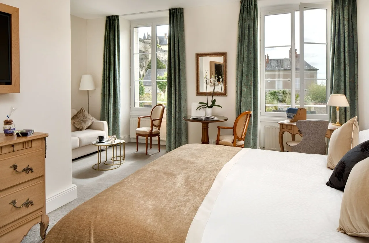 Bedroom with white interiors and brown and green accents at Le Manoir Les Minimes, Amboise
