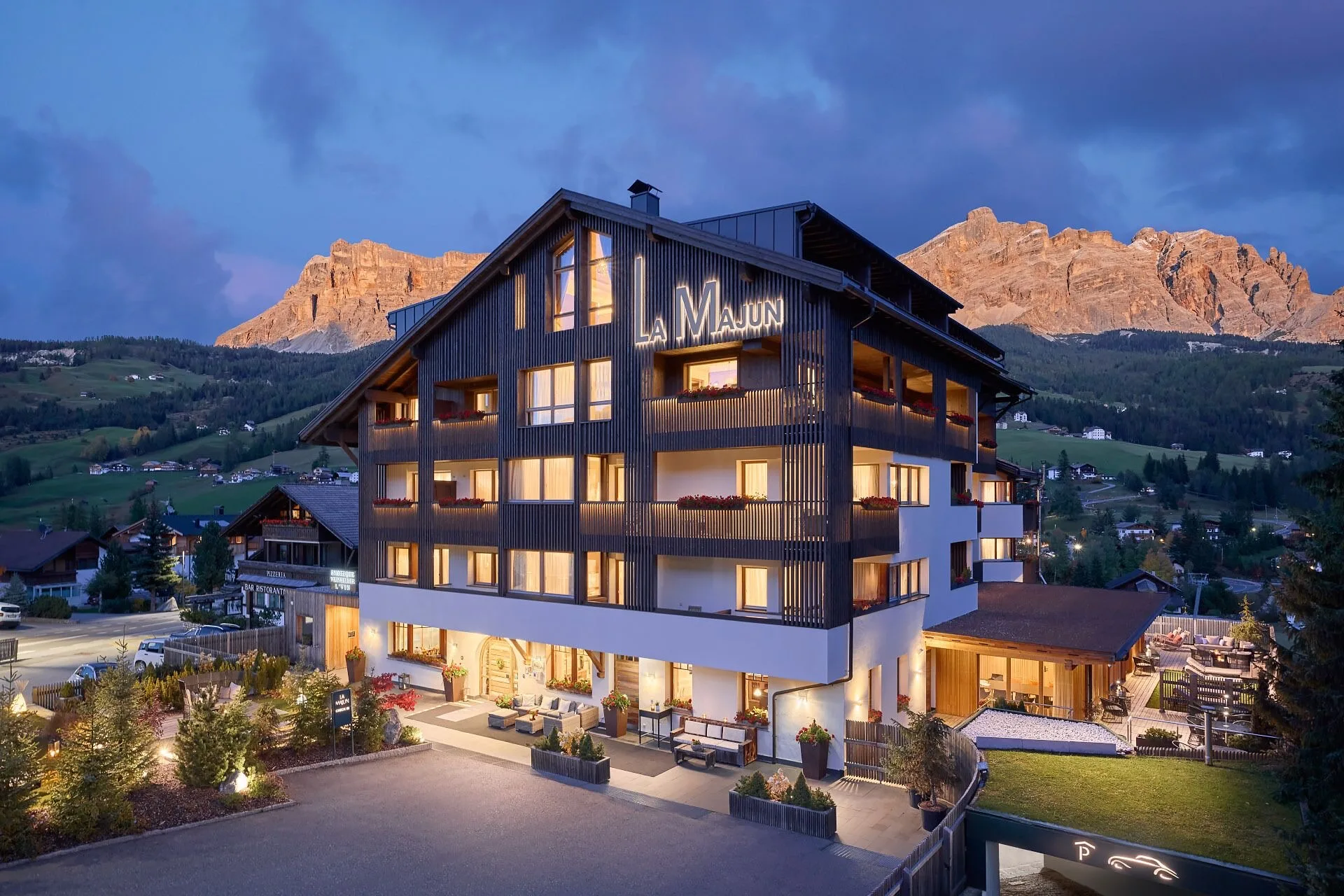 Distant view of Hotel La Majun in La Villa with alpine architecture and mountain surroundings