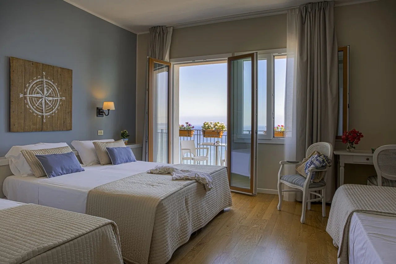Bedroom at Hotel Punta Nord Est with wood-style vinyl flooring and pale blue and green painted walls