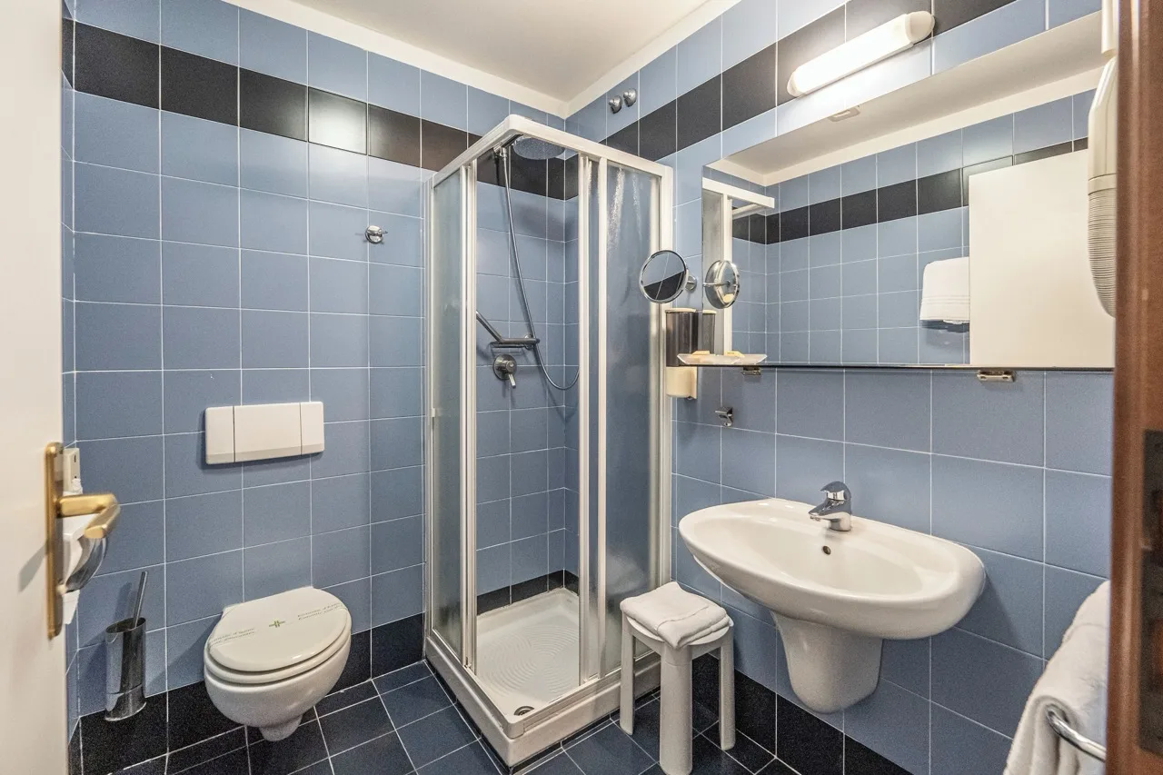 Bathroom at Hotel Italia in Corvara with pale blue tiles and simple fixtures