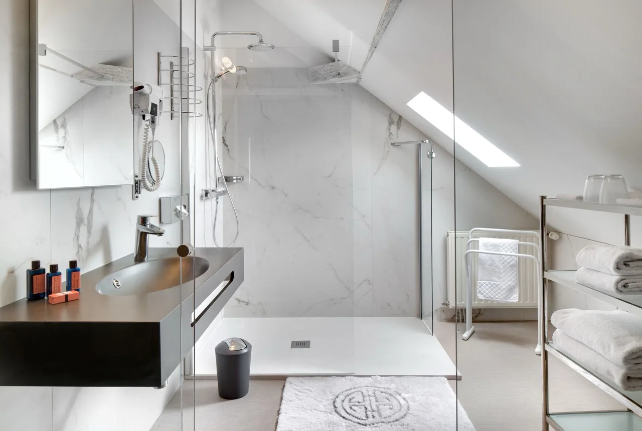 Bathroom with white tiles, black sink, and shower at Le Manoir Les Minimes Amboise