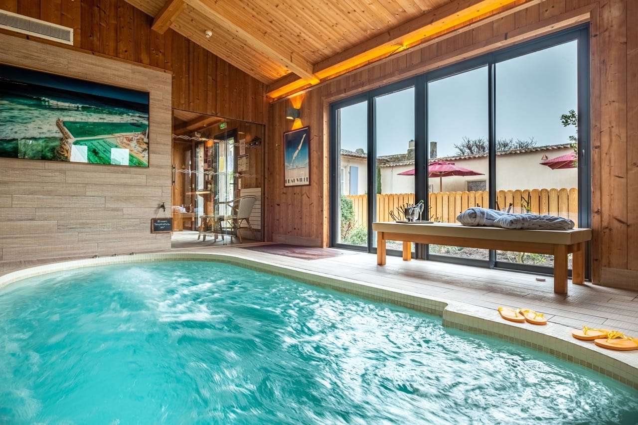Indoor pool at La Baronnie Hôtel & Spa - Teritoria Saint-Martin-de-Ré with wooden floor and glass sliding doors