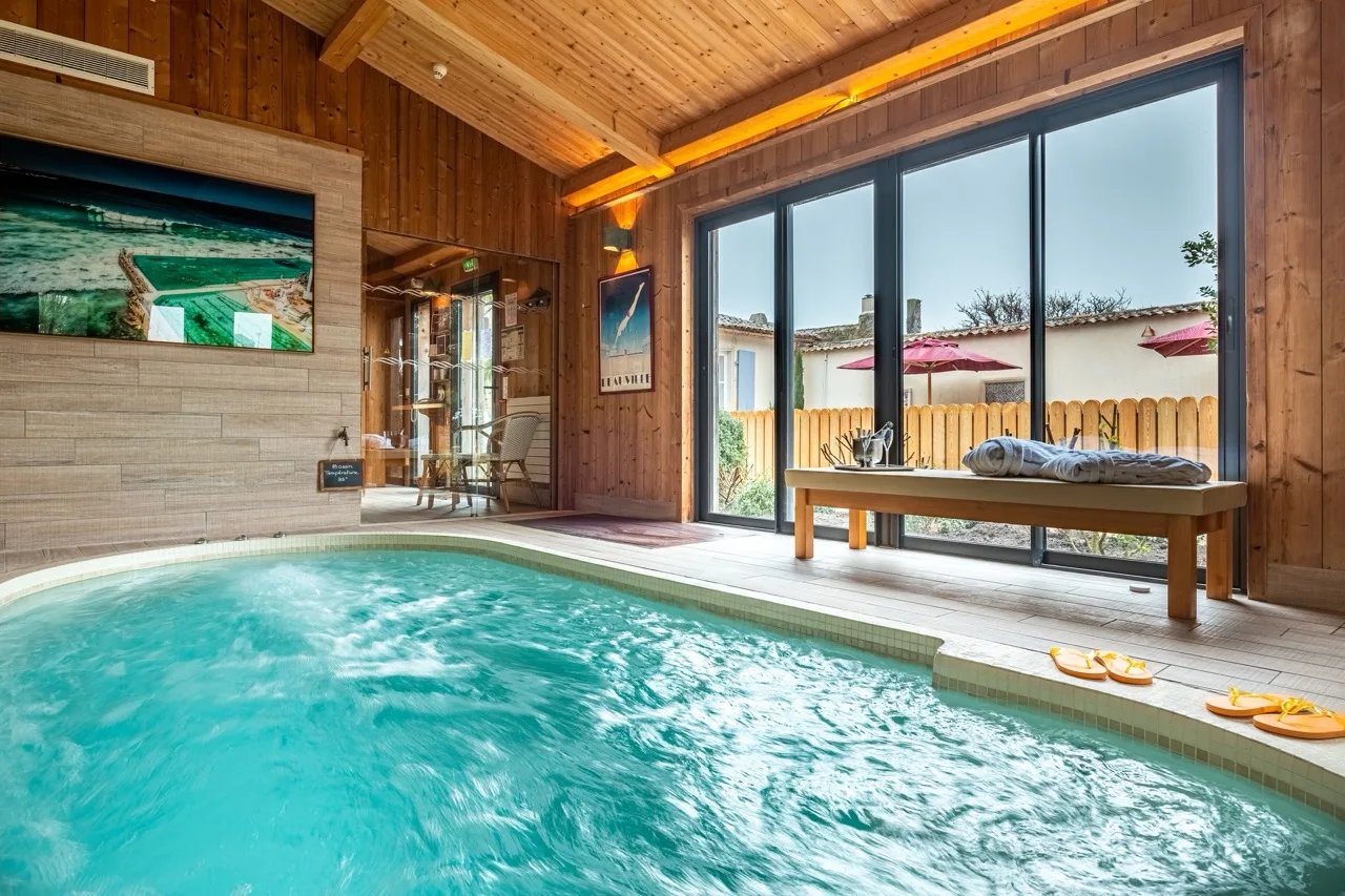 Indoor pool at La Baronnie Hôtel & Spa - Teritoria Saint-Martin-de-Ré with wooden floor and glass sliding doors