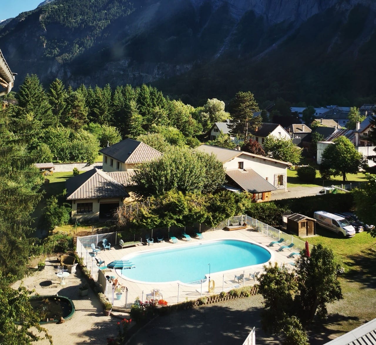 Outdoor view at Sport'Hotel-Aparthotel de Milan Le Bourg-dʼOisans showing pool, trees, and mountains