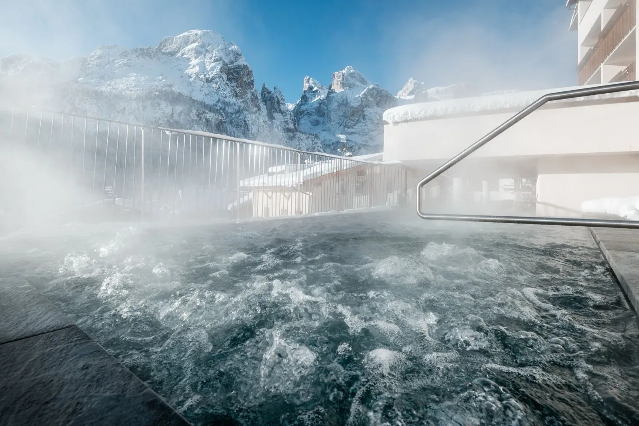 Outdoor pool on upper floor of Hotel Gran Ciasa with steam, overlooking snowy mountain landscape