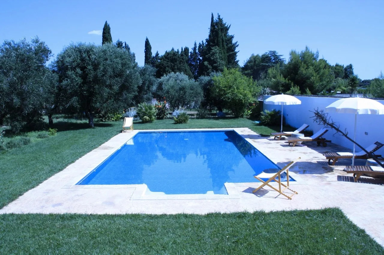 Outdoor pool at B&B Villa Giuliana in Arnesano, surrounded by greenery and a peaceful garden setting