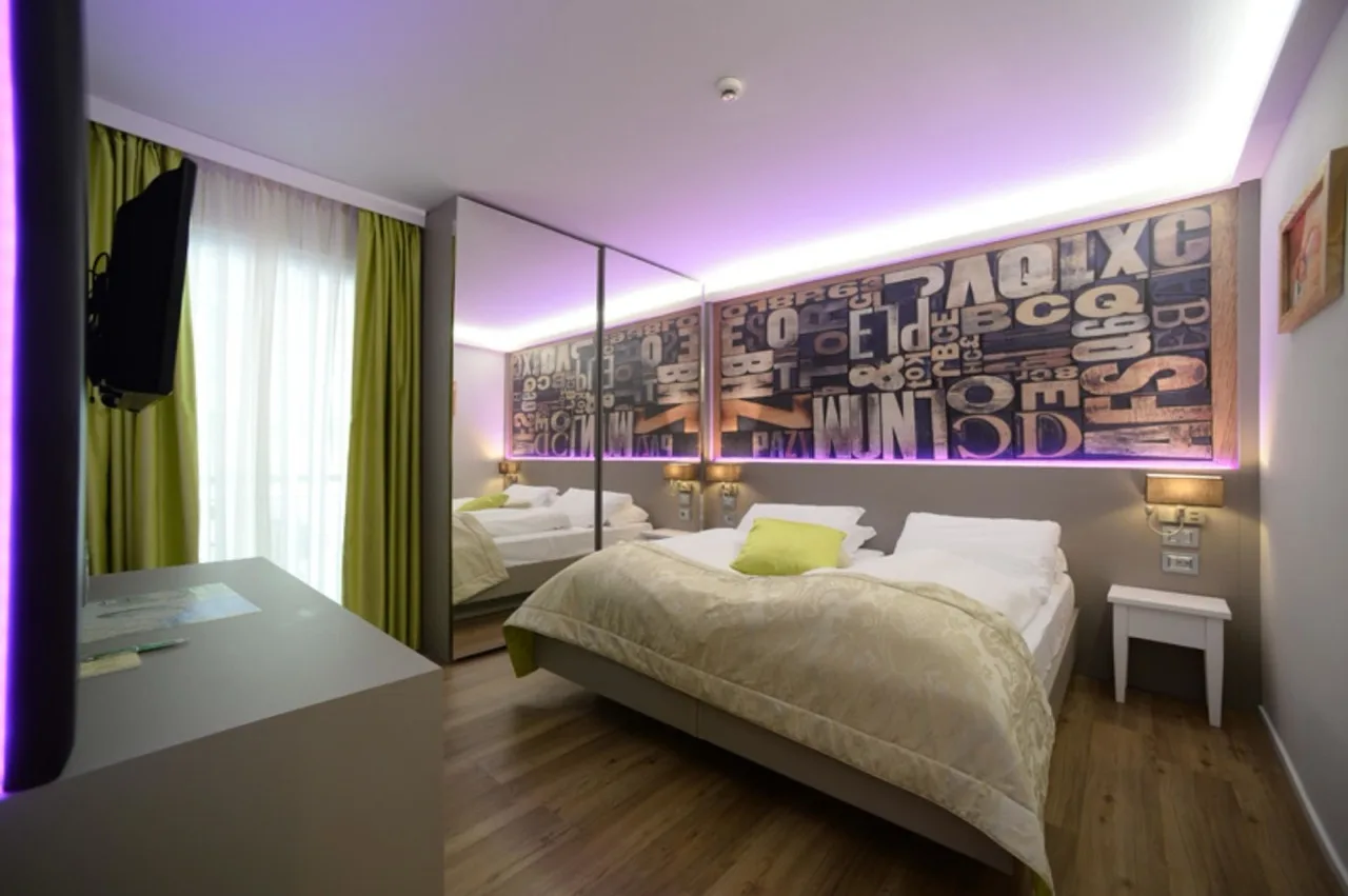 Bedroom at Aktivhotel Santalucia with vinyl flooring and a graphic wall of random letters above the bed