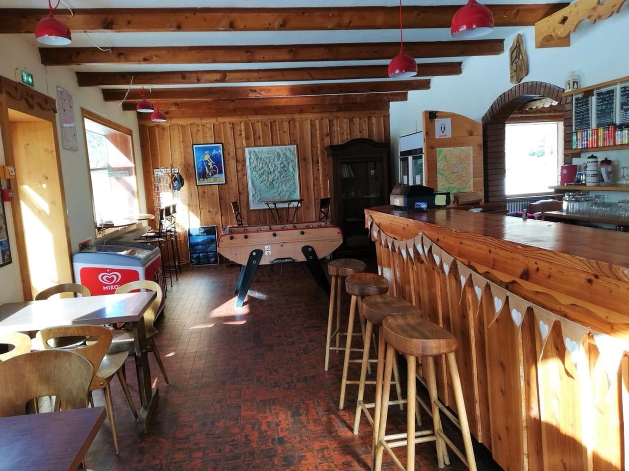 Wooden bar and stools with tables and chairs in rustic lounge at Gite - Auberge Le Chamois Col d'Ornon