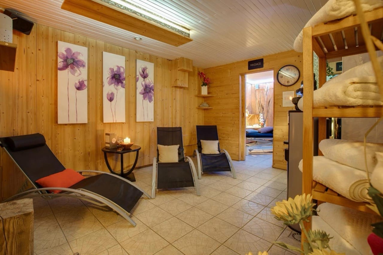 Relaxation room at Hôtel Le Castillan in Alpe d'Huez with lounge chairs candles towels and floral wall art